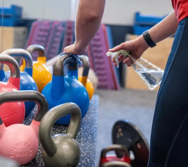 Coach cleaning kettlebells in the gym
