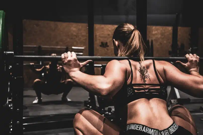 Woman back squatting with a barbell in a gym